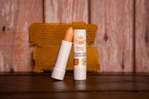 Bálsamo labial reparador con filtro solar e propóleo natural, sobre fondo de madera y panal de abejas